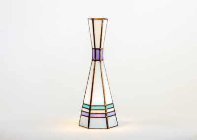 A tall, slender vase with geometric patterns in gold, purple, and green.