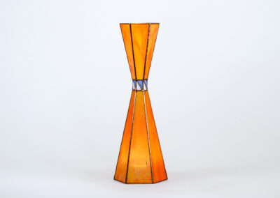 A tall, orange hourglass-shaped lamp with metallic accents.