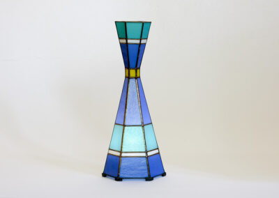 Stained glass vase with geometric blue and yellow patterns.