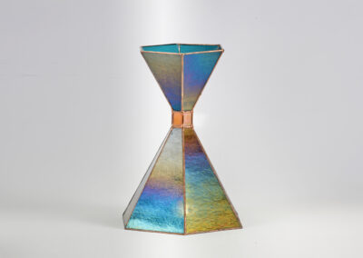 A metallic hourglass-shaped object with a rainbow sheen.