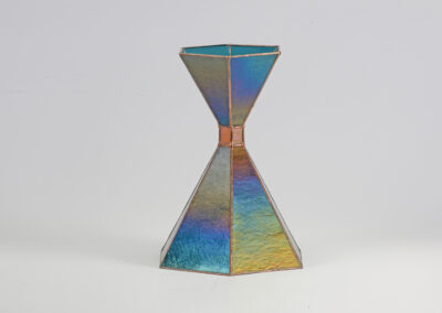 A metallic hourglass-shaped object with a rainbow-like sheen.