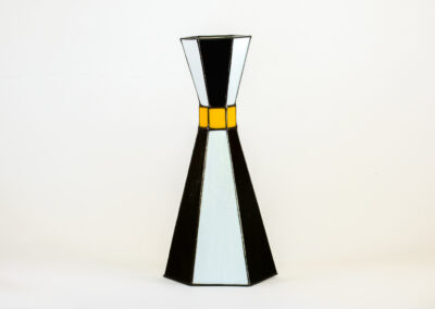 A tall, black and white vase with a gold band near the top.