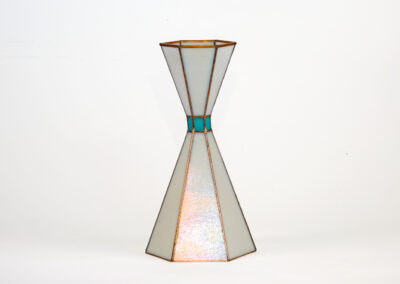 A geometric, hourglass-shaped lamp with stained glass panels.