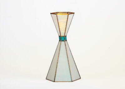 A modern geometric glass vase with a narrow middle and wide top and bottom.