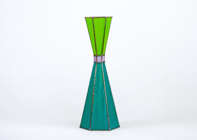 A tall, green geometric sculpture with a narrow middle section.