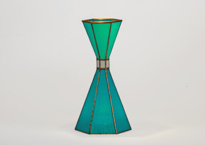 A modern green hourglass-shaped vase with gold accents.