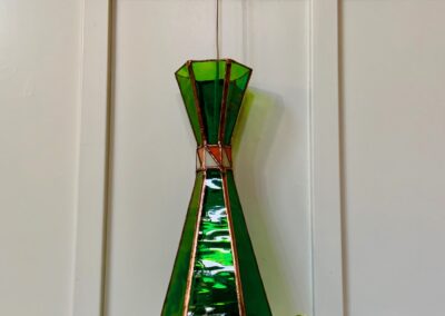 A green stained glass vase on a wooden surface.