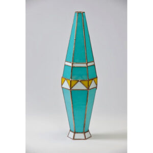 A tall turquoise stained glass lamp with geometric patterns.